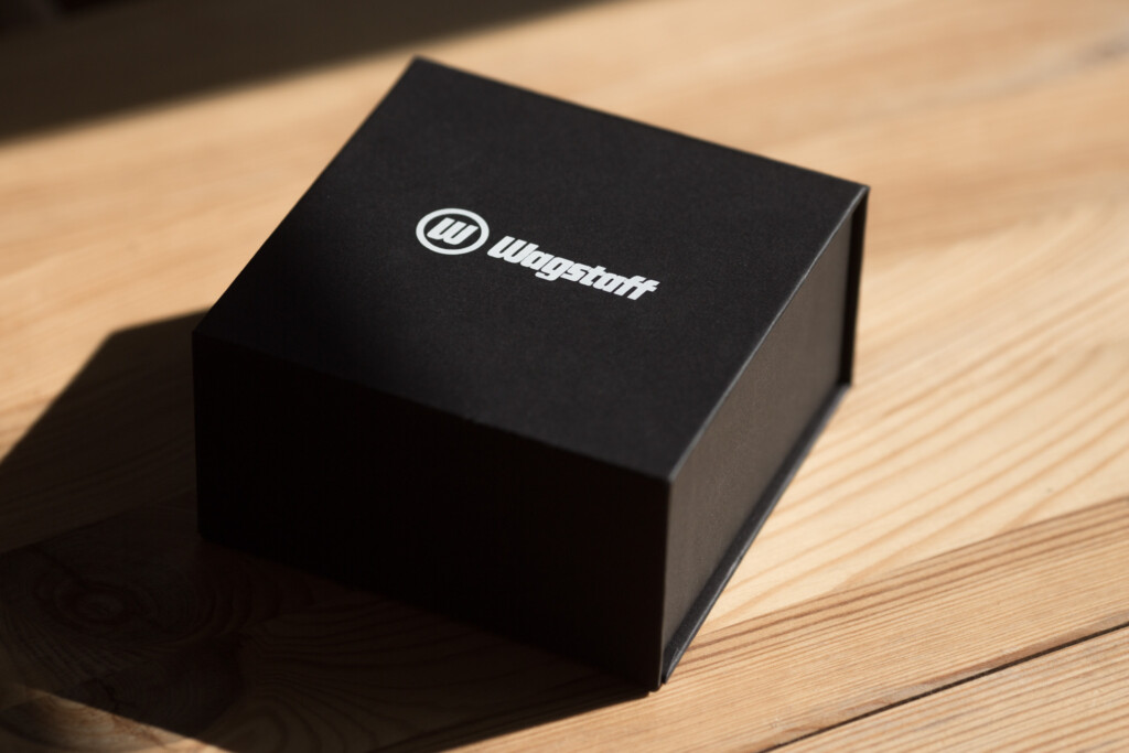 Black rigid box with embossed Wagstaff logo on lid, placed on wooden surface.