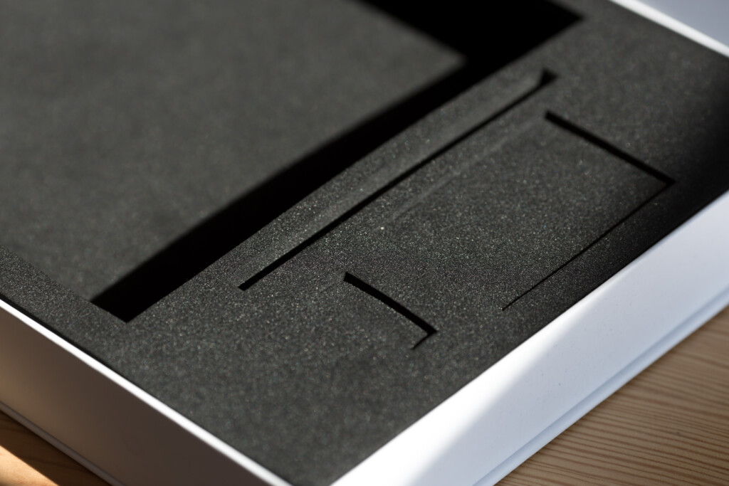 Rigid boxes with black textured foam inserts, white outer edge visible, stacked and angled to show compartment structure.