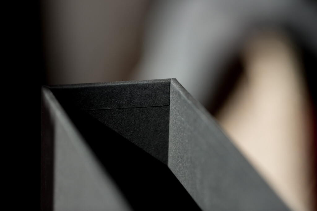 Close-up of folded black rigid box corner showing matt finish and sharp edge detail.