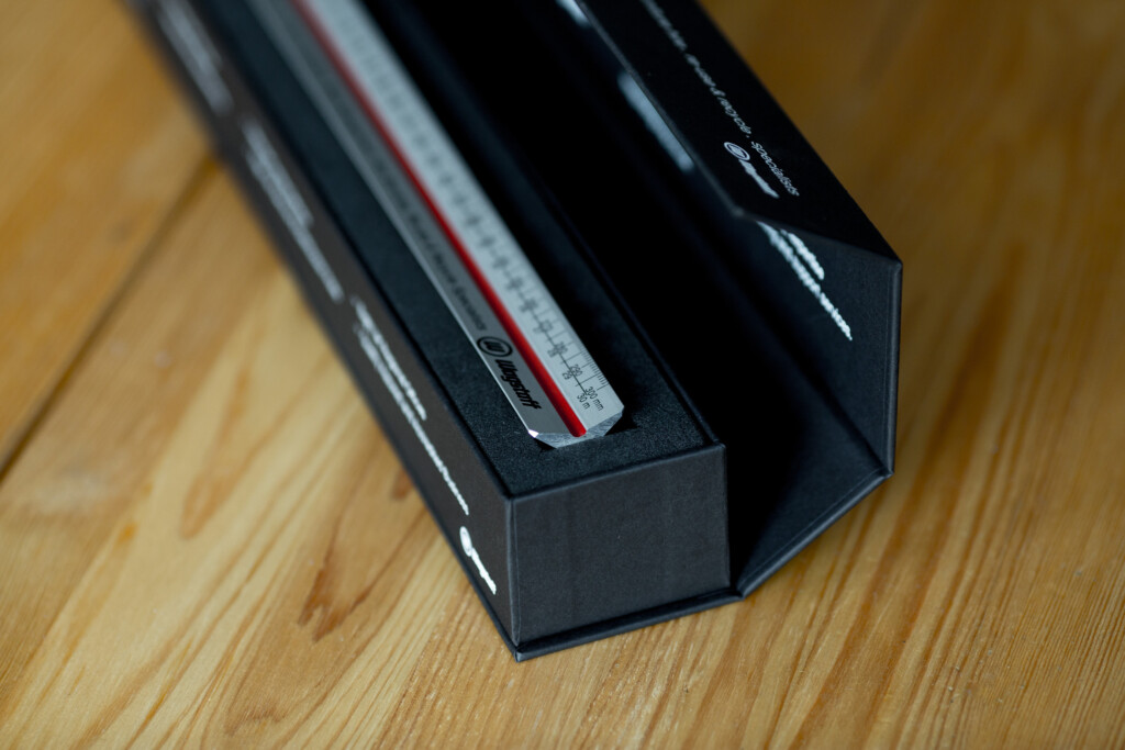 Black rigid box with white label and red stripe detail, displayed open on wooden surface.