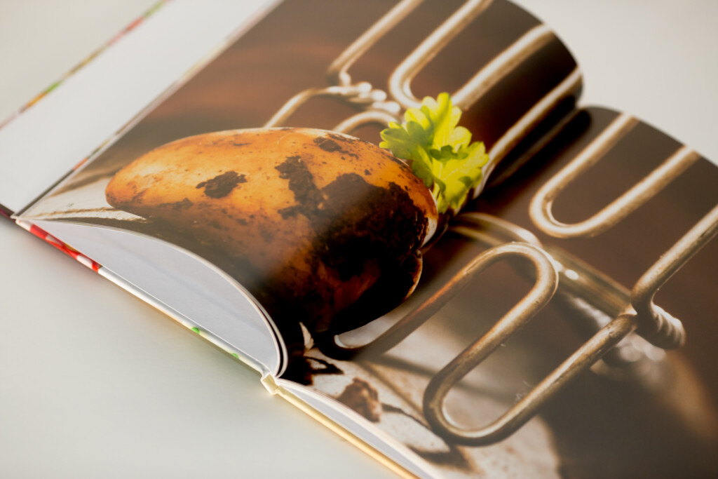 Hardcover book with embossed cover displayed open on stacked volumes, featuring a photograph of a beetroot with green leaves
