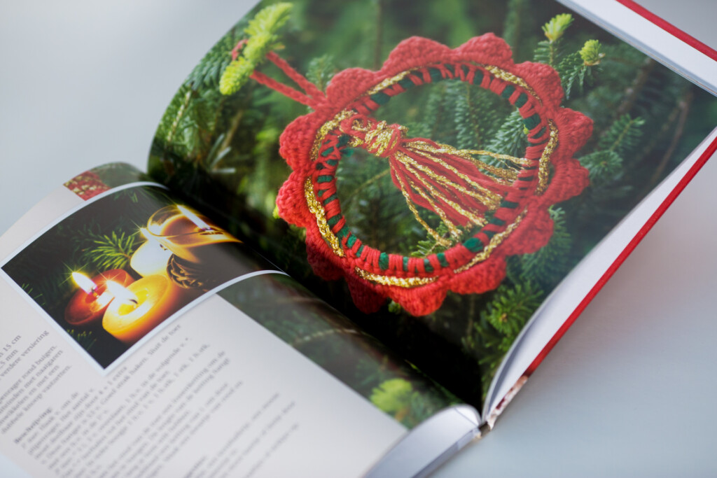 Hardcover book open to a spread showing red embroidered textile detail on green fabric, with additional product pages