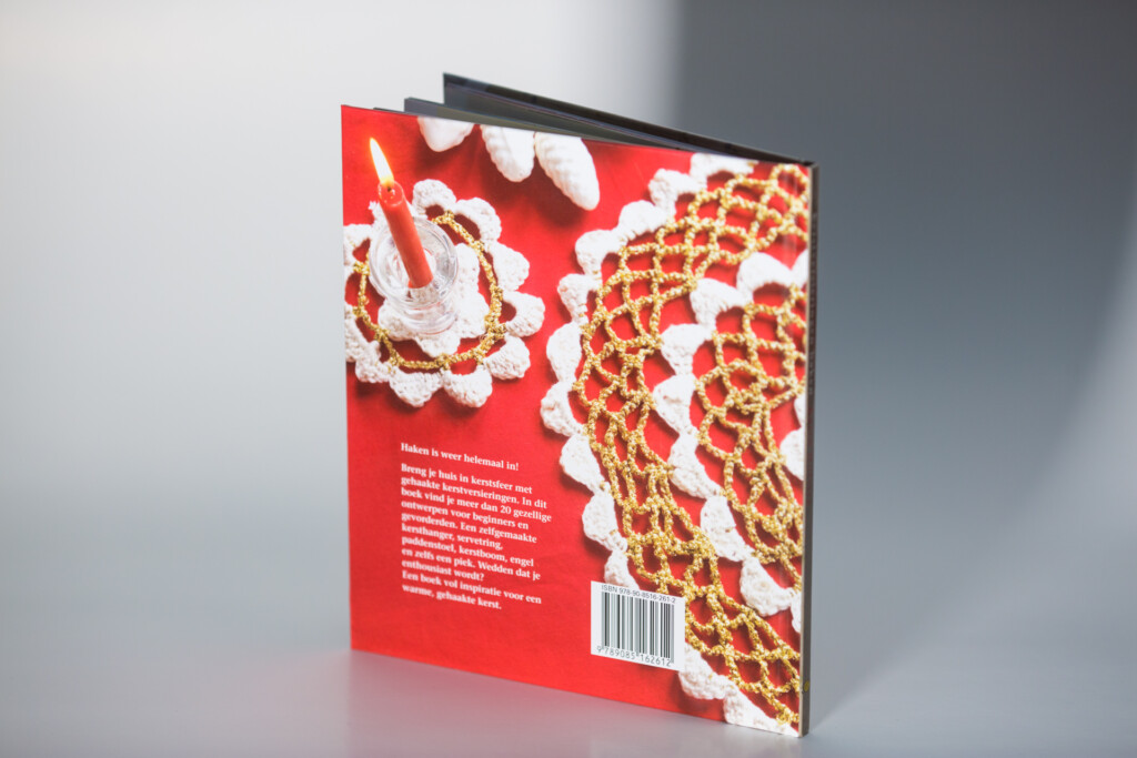 Hardcover book with red cover featuring white and gold decorative floral lace pattern designs and embossed detailing.