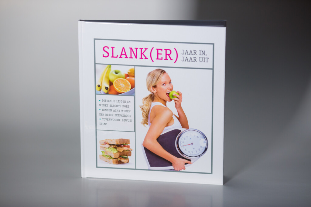 Softcover book titled Slank(er) Jaar In Jaar Uit with cover images of fruit, a woman holding a scale and an apple, and a