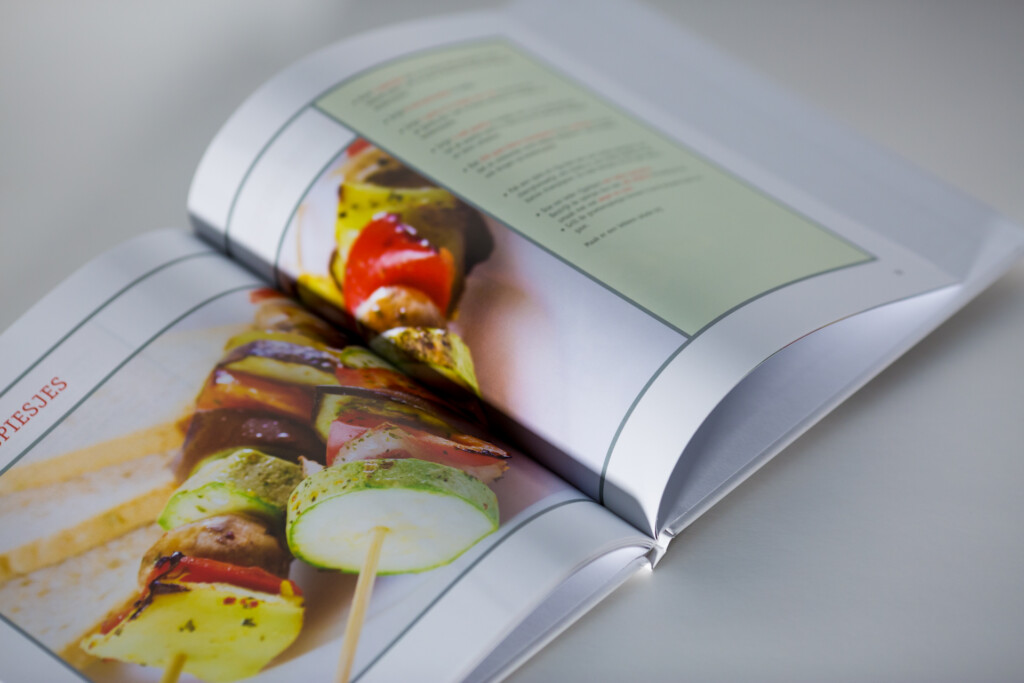 Open hardcover cookbook showing grilled vegetable skewers on left page with recipe text on right page.