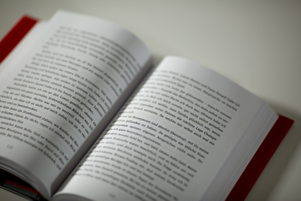 Open hardcover book with red ribbon bookmark, displaying text pages in close-up focus.