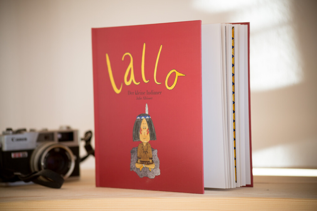 Red hardcover children's book titled "lallo" with gold foil-stamped text and pear illustration, displayed next to a vintage