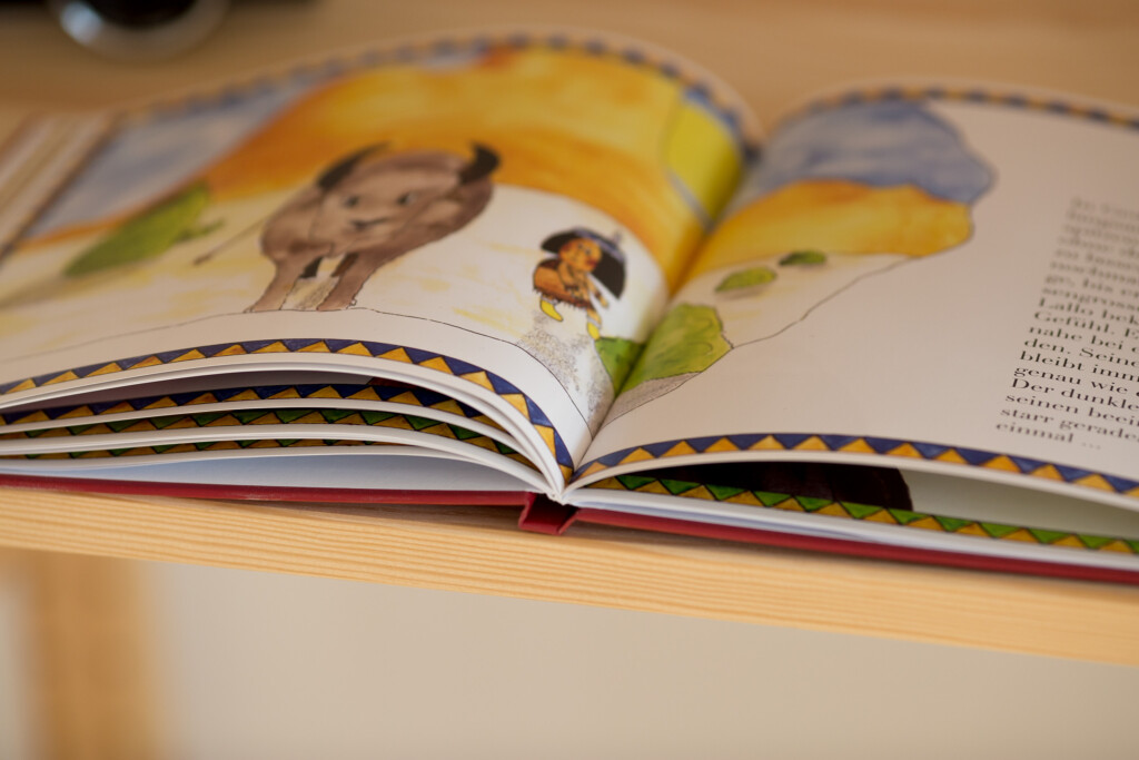 Open children's book showing illustrated pages with a banana and bird character, displaying printed colour artwork and