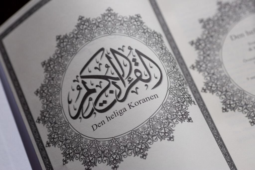 Hardcover book cover featuring Arabic calligraphy and ornamental border design with Swedish text "Den Heliga Koranen" below.