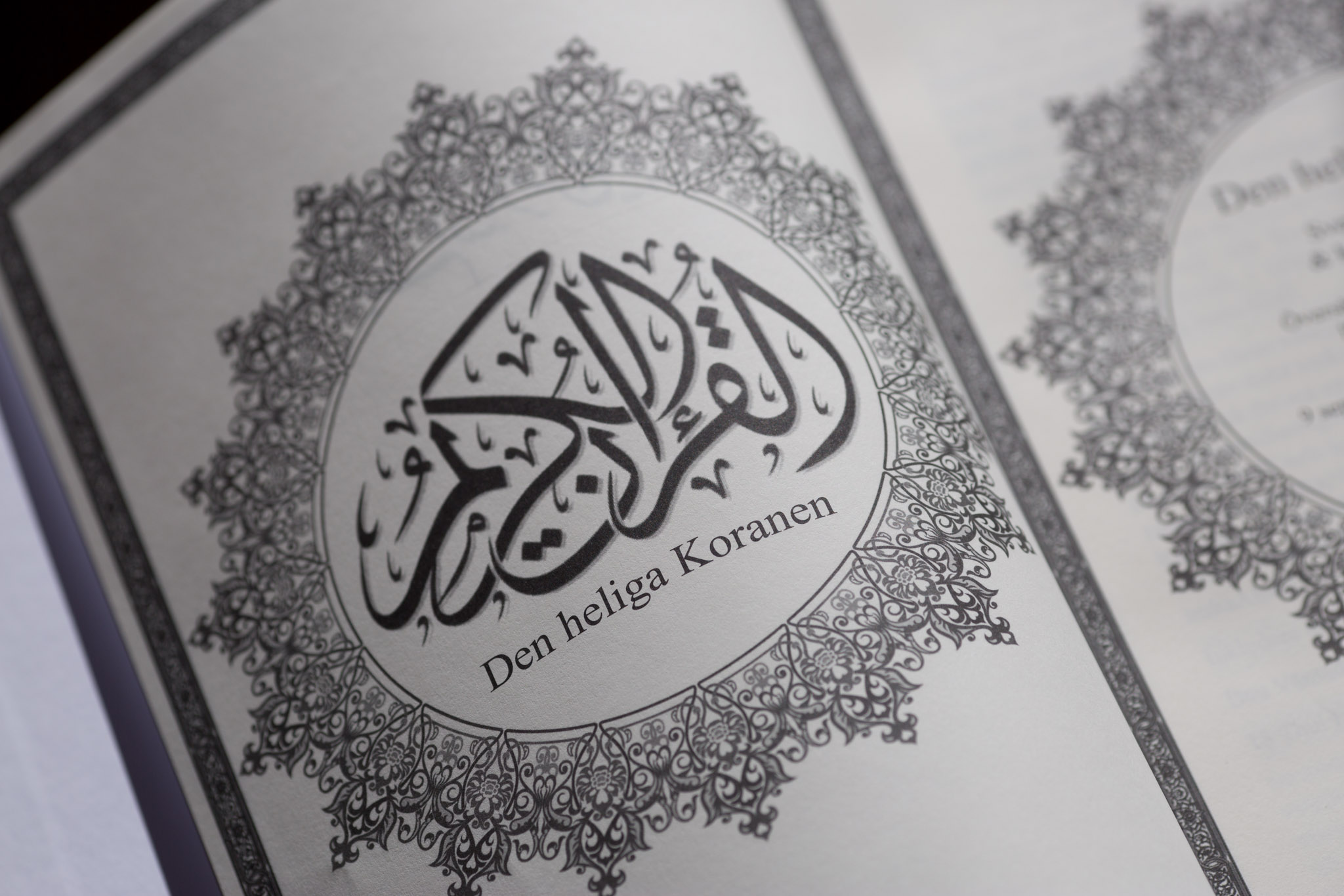 Hardcover book cover featuring Arabic calligraphy and ornamental border design with Swedish text "Den Heliga Koranen" below.