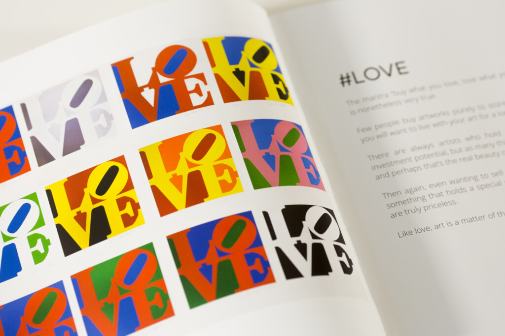 Printed art book spread with colourful pop art style "LOVE" design in multiple colour variations on left page and "#LOVE"