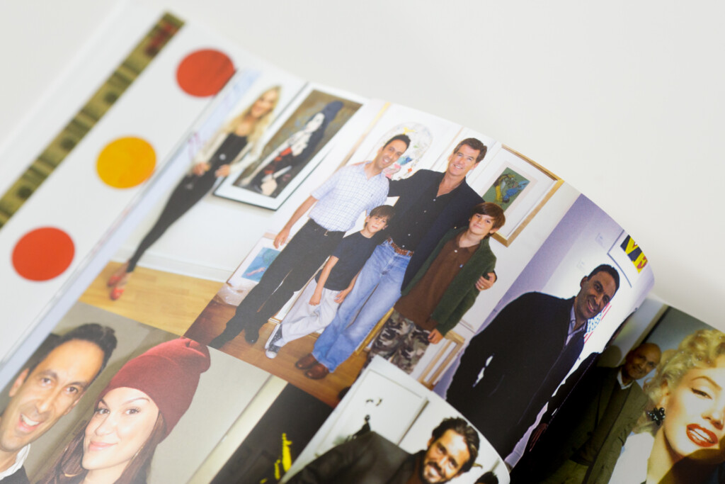 Printed photo album or catalogue open showing multiple colour photographs of people and groups, with colour swatches visible