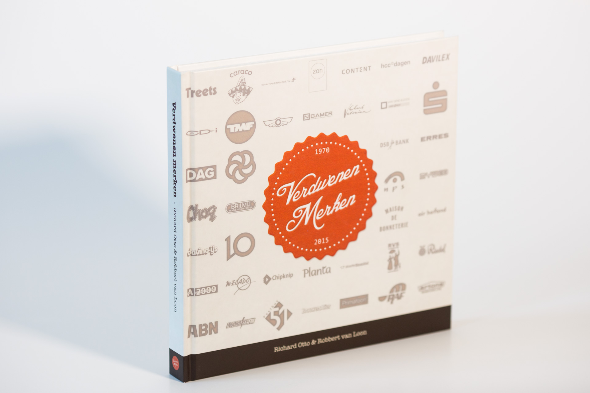 Hardcover book with "Verdwenen Merken" orange badge on cover surrounded by various Dutch brand logos, spine visible against