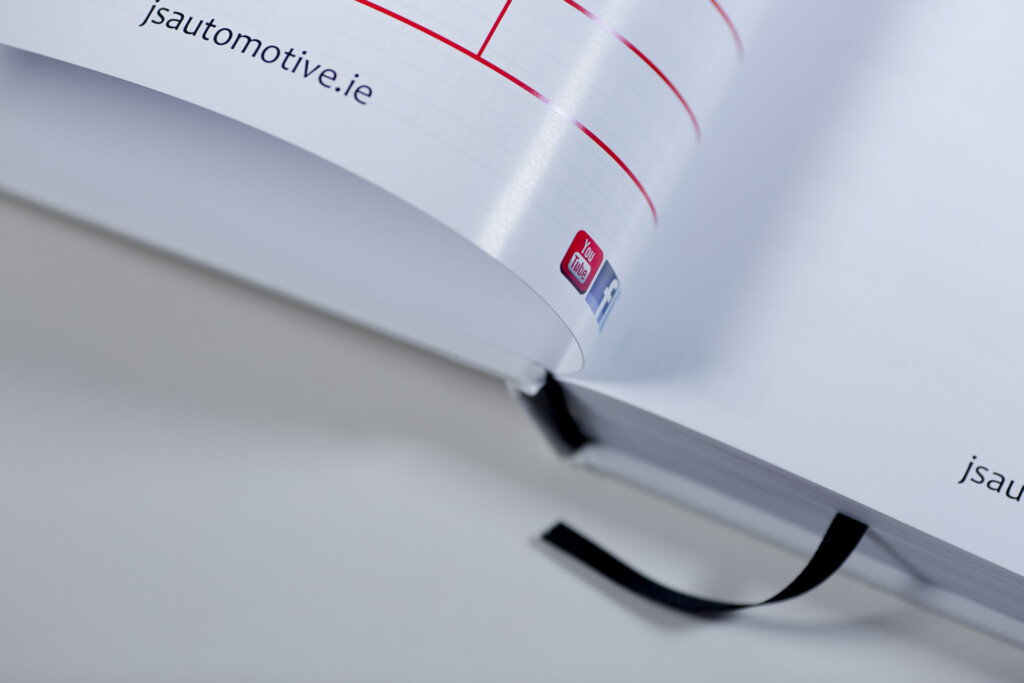 Hardcover diary with grey cloth binding and red stitching detail on spine, displayed open at an angle.