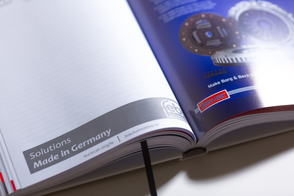 Open hardcover catalogue with blue cover featuring circuit board design, displayed on white background