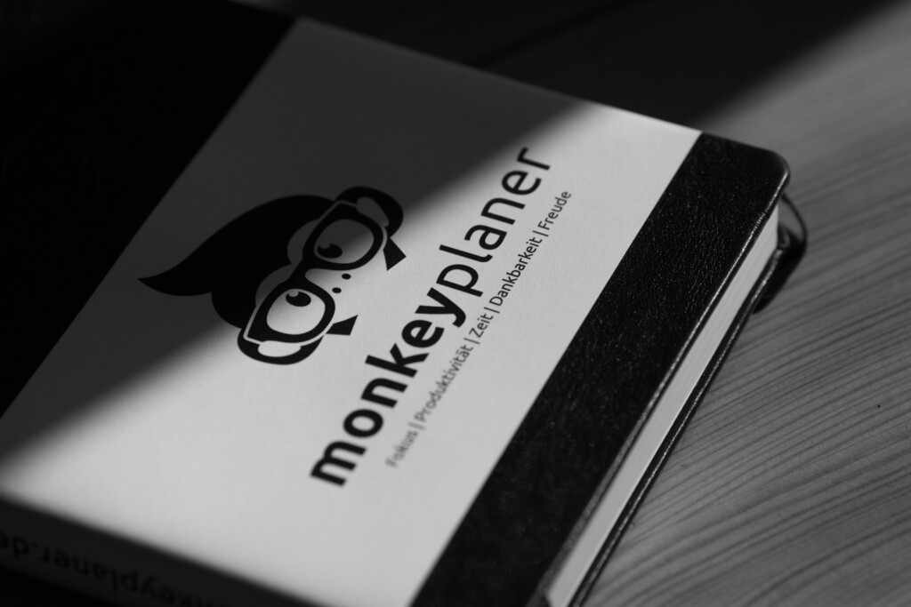 Monkey Planner hardcover notebook with black foil-stamped owl logo on white cover and black fabric spine.