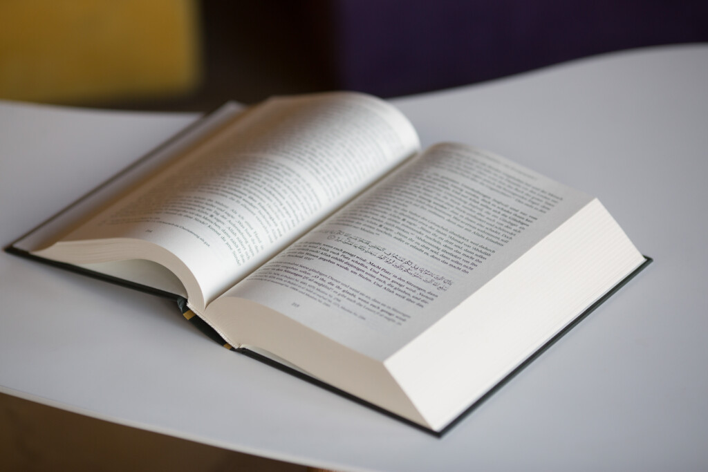 Open hardcover book with printed text pages, showing sewn binding and white endpaper.