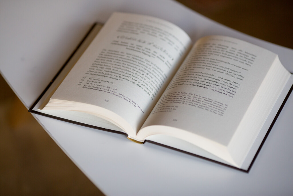 Hardcover book with open pages showing printed text, displayed on white surface.