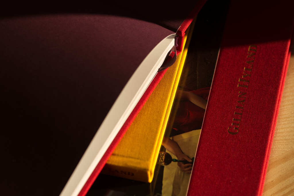 Hardcover books with red cloth binding and gold-stamped spines, fanned to show binding and cover finish detail.