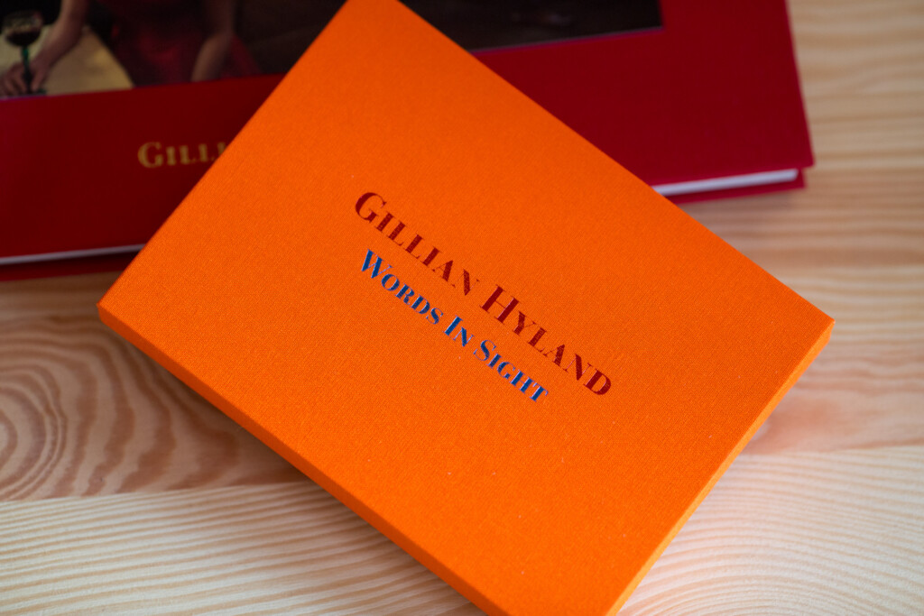 Bright orange hardcover book with "GILLAN HETLAND WORDS IN NIGHT" stamped on cover, displayed on wooden surface with
