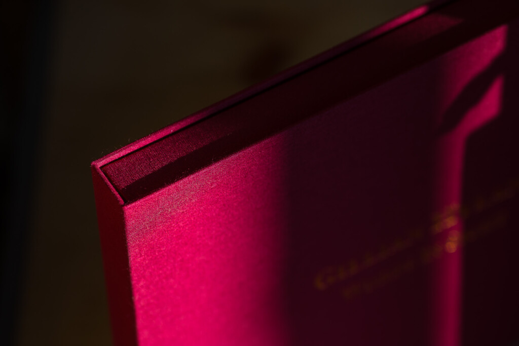 Hardcover book with hot pink foil-stamped cover and embossed spine detail, shot in studio lighting.