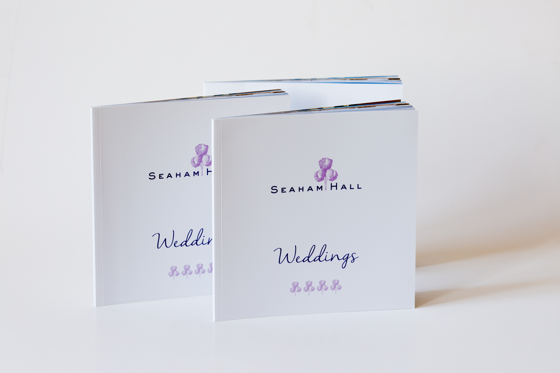 Two white hardcover Seaham Hall Weddings brochures with purple logo and text, stacked at an angle.