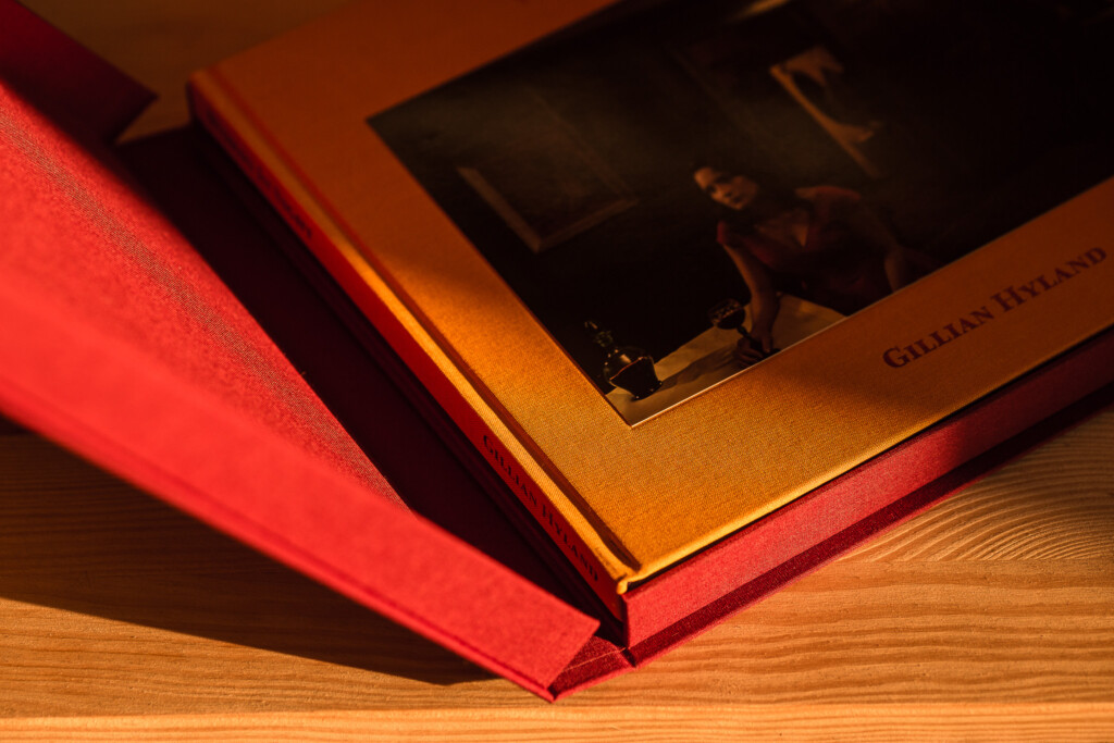 Hardcover books with red cloth spine and gold-stamped cover fanned out on wooden surface, showing binding detail.
