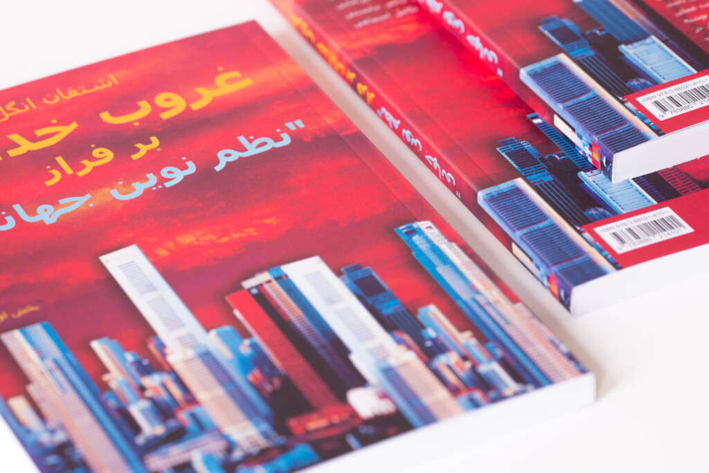 Stack of red hardcover books with blue cityscape imagery and Arabic text on covers, showing closed spines and fanned pages.