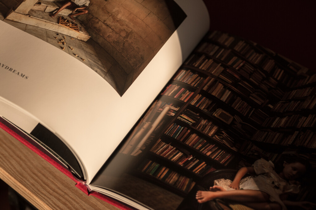 Open hardcover book with photograph of library interior on left page and shelving visible on right page, pink ribbon