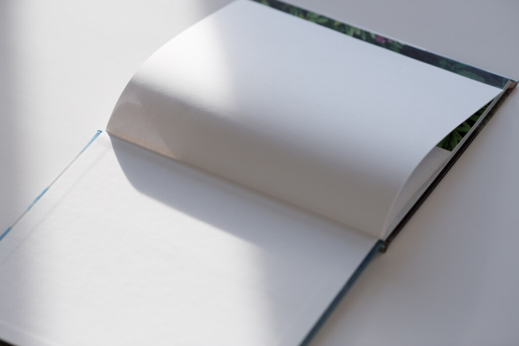Open hardcover book with white pages and blue ribbon bookmark, displayed against white background.