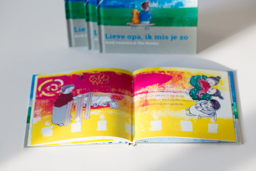 Hardcover children's book "Lieve opa, ik mis je zo" open to colourful spread with illustrations and white cut-outs, with