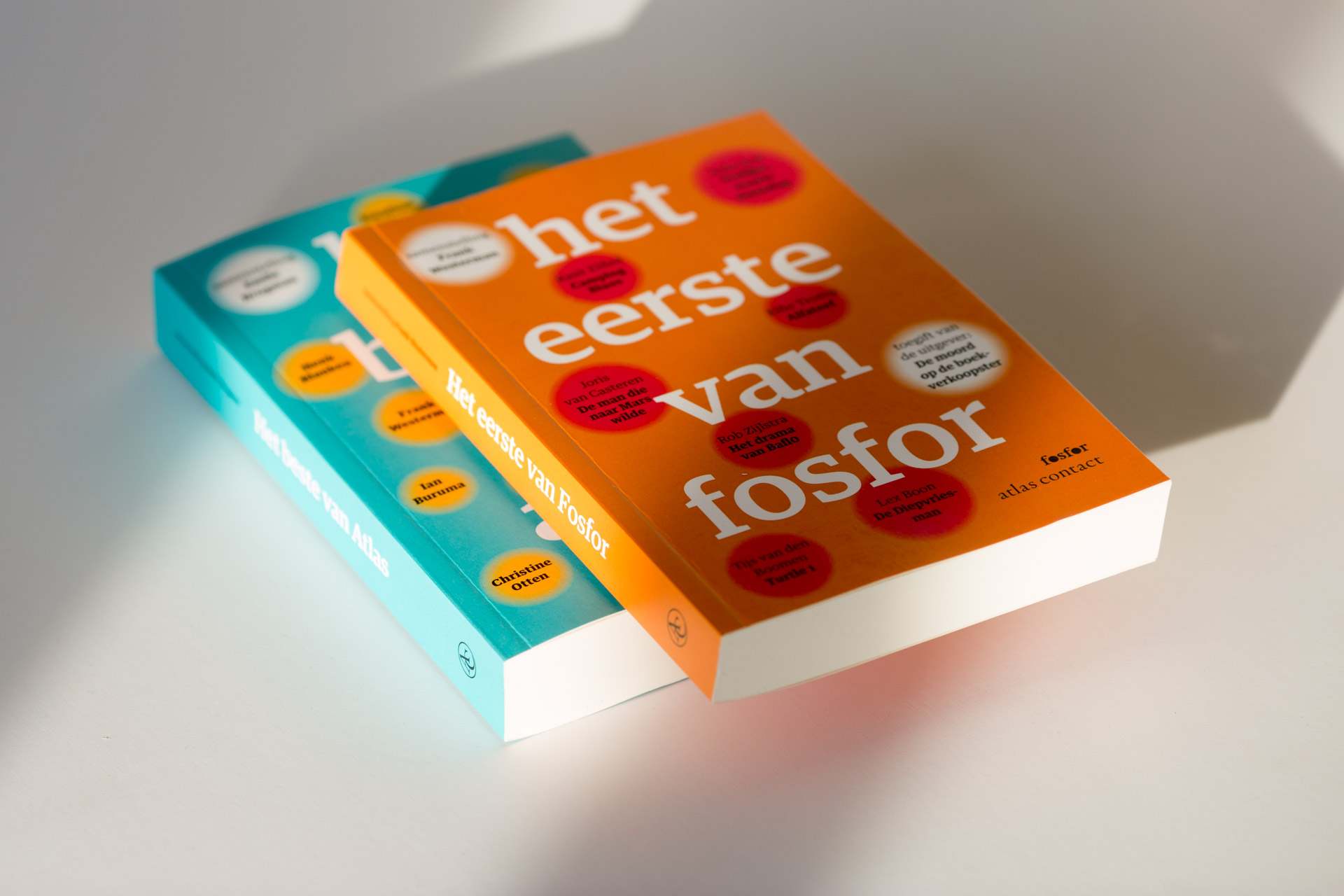 Two softcover books stacked, one with turquoise spine and one with orange cover titled "het eerste van fosfor", both with