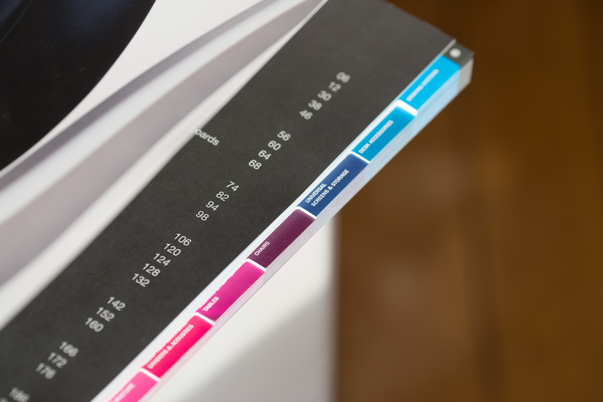 Printed catalogue with coloured index tabs in light blue, dark blue, burgundy and pink along the right edge.