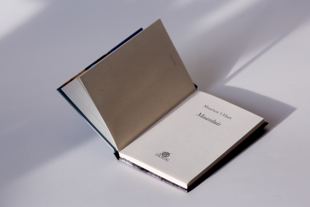 Hardcover book with dark binding open to show title page and tan endpaper, photographed against white background.