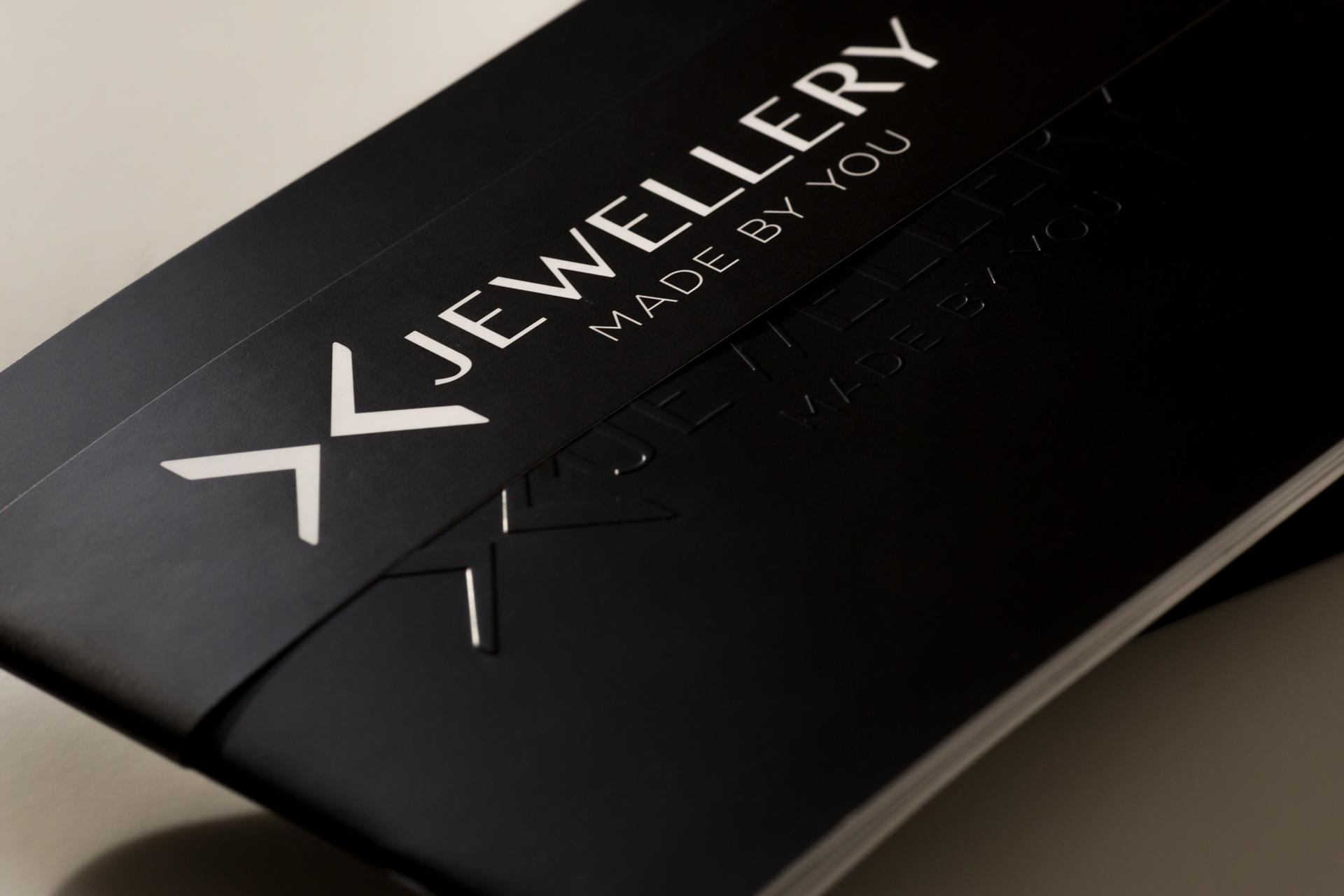Black soft-cover catalogue with white "XJewellery Made By You" text and logo on front cover.