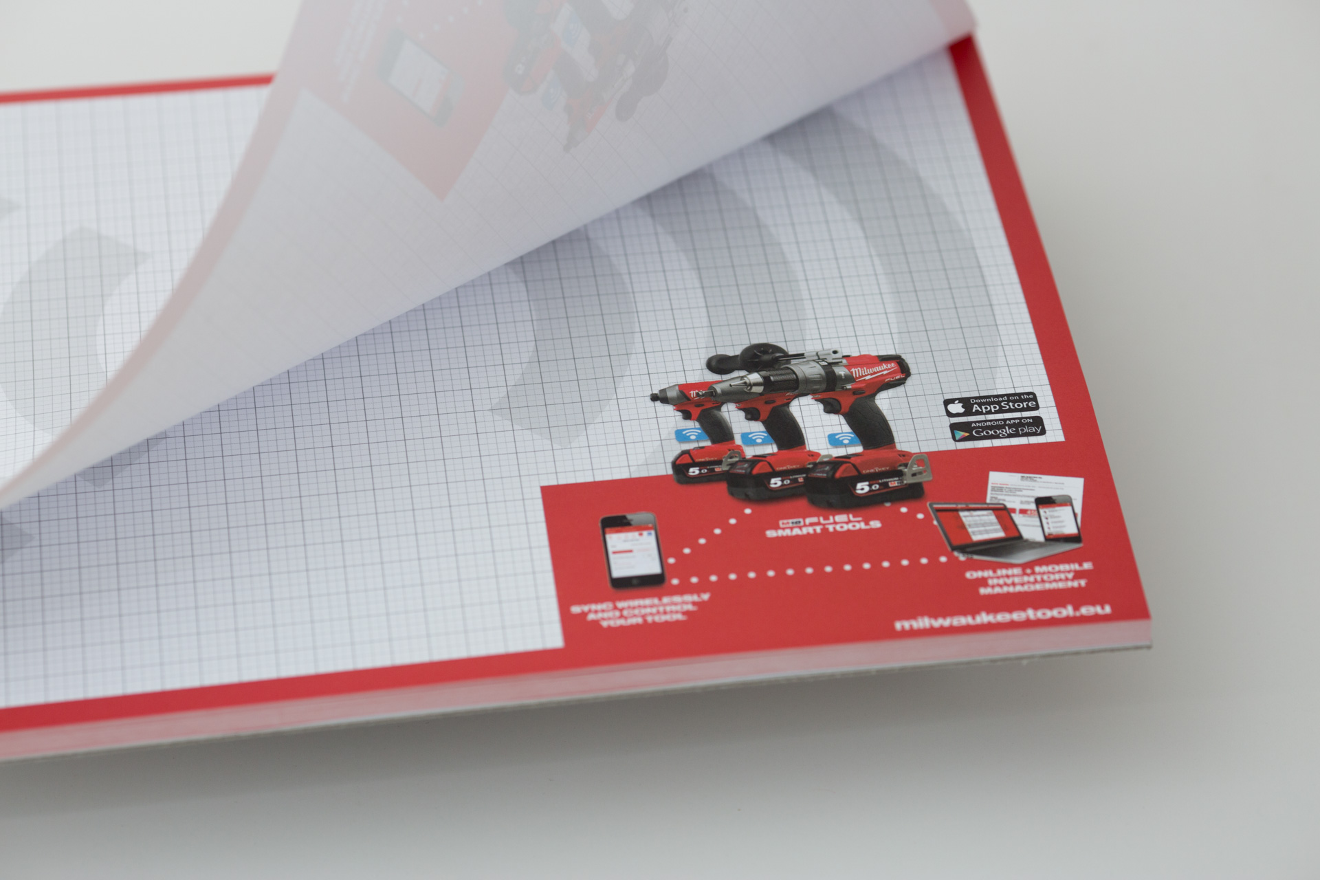 Red and white catalogue with drill and driver tool imagery, displayed open at an angle showing product layout and