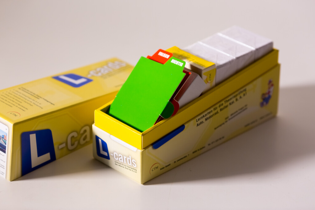 Yellow box of assorted learning cards with coloured card samples fanned out inside, showing green, yellow, white and other