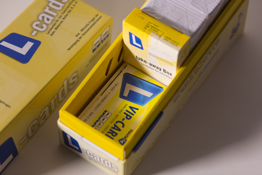 Yellow rigid boxes with blue branding and take-away box insert containing layered cards or materials.
