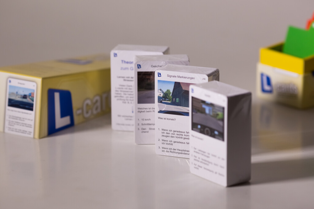 Printed product boxes displaying digital content pages with photographs and text, arranged in a studio setting with yellow