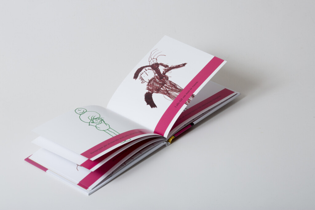 Open softcover book with pink ribbon bookmarks, showing illustrated pages with botanical and figure drawings in brown and