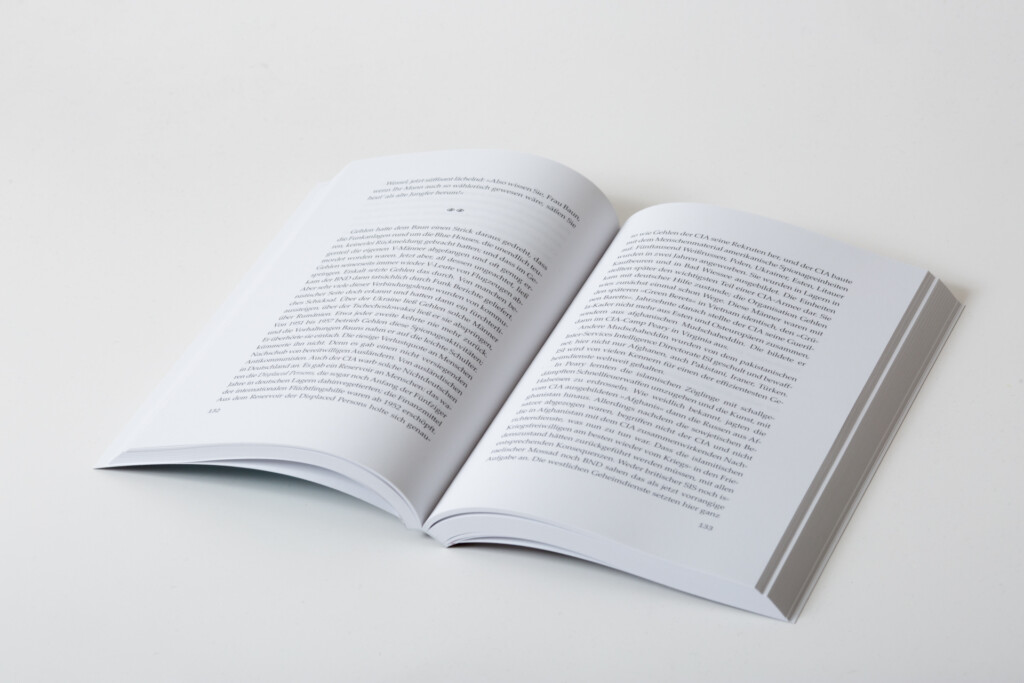 Open book with text pages, showing sewn binding and white paper stock against a neutral background.