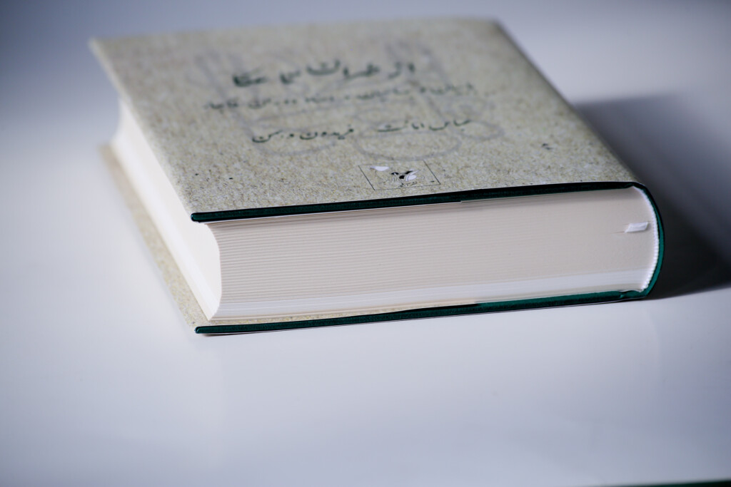 Closed hardcover book with grey textured dust jacket and green ribbon bookmark visible along spine edge.