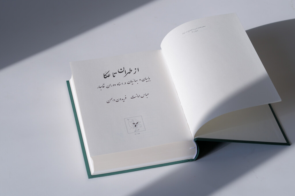 Hardcover book with teal binding and dust jacket, open to show interior pages with Arabic text and a small illustration.