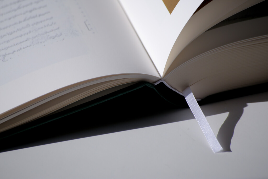 Open hardcover book with dust jacket showing text on left page and binding detail.