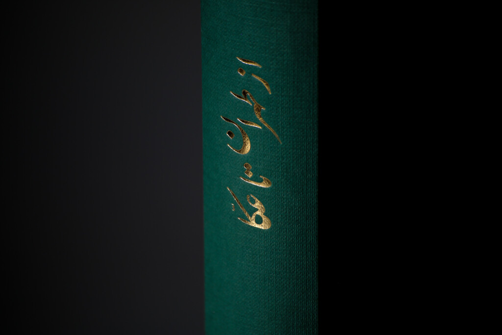 Teal hardcover book spine with gold foil-stamped text against dark background.