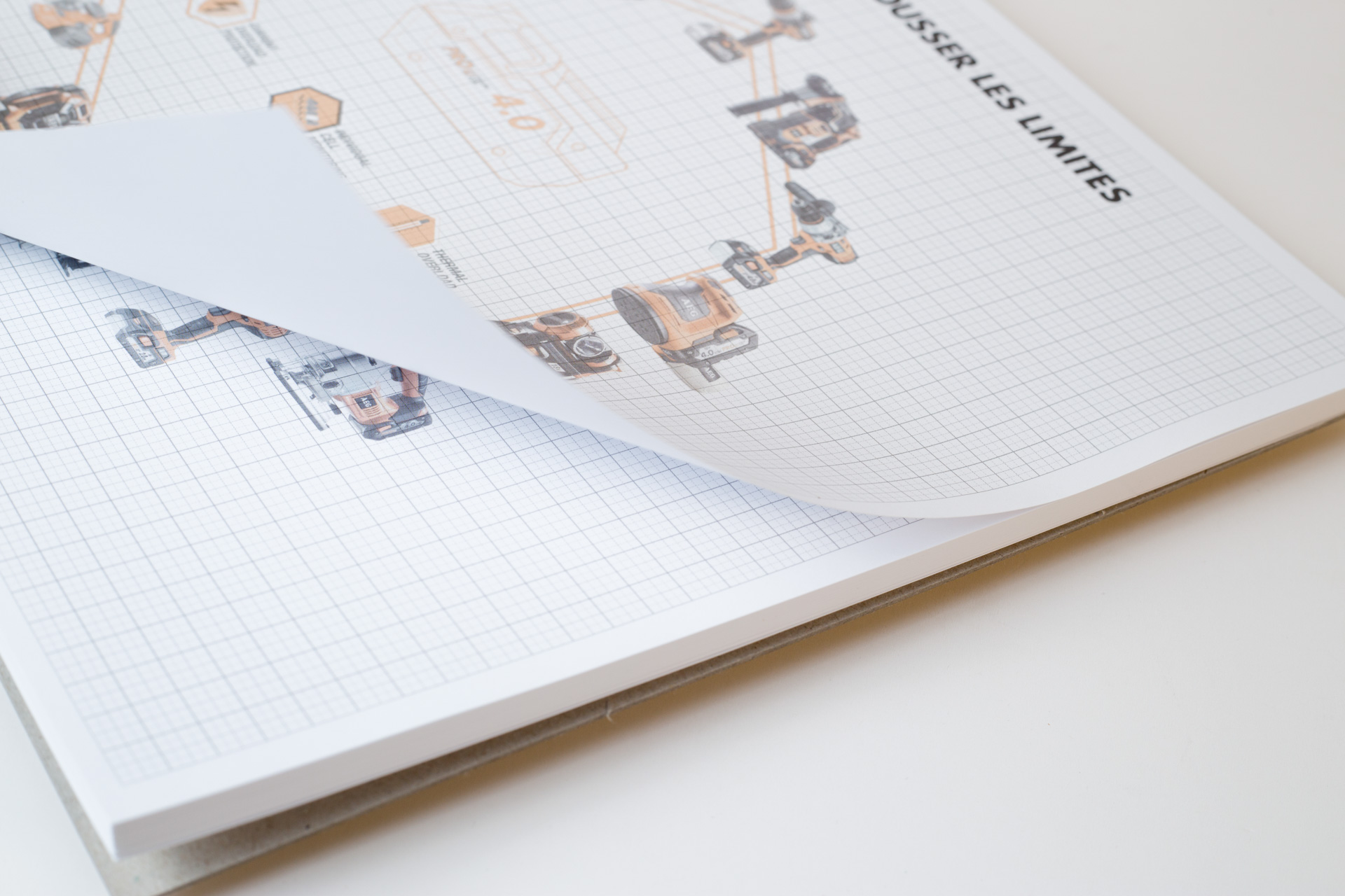Printed writing pad with grid layout and small photographs arranged in a chart pattern on the upper page.