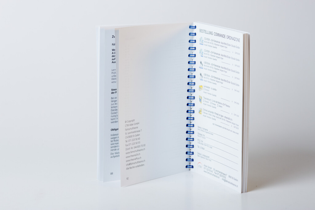 Wire-o bound notebook with blue spiral binding and tabbed index pages printed with text and checkbox lists.