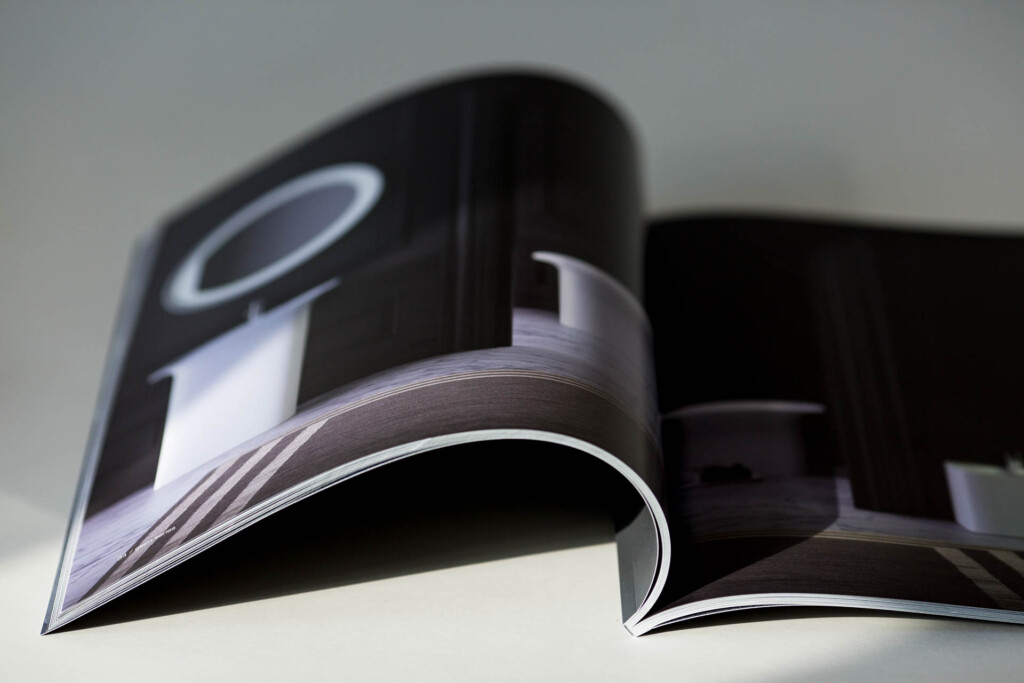 Glossy laminated catalogue with open spread fanned alongside closed copies, showing high-quality colour printing and
