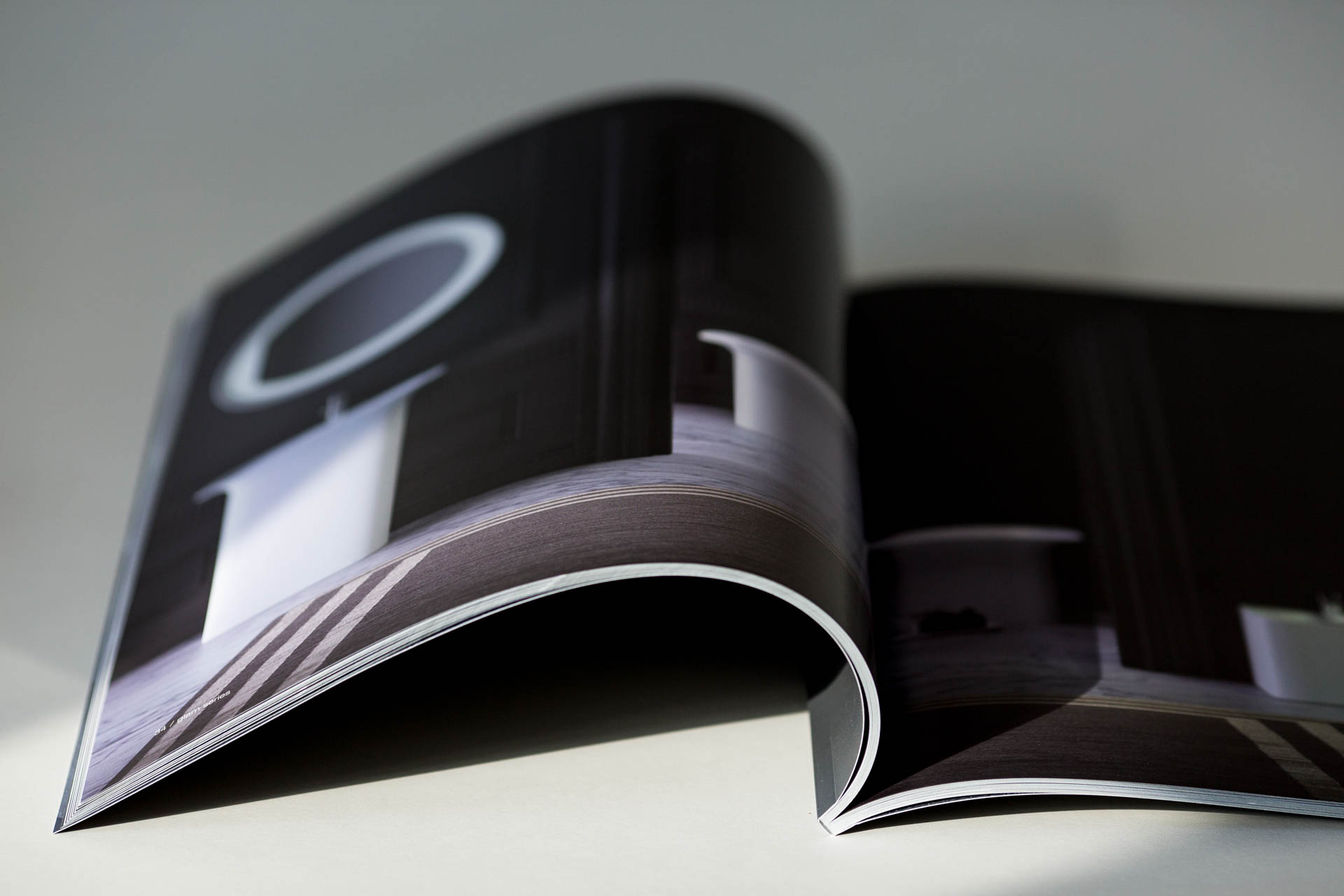 Hardcover catalogue with gloss laminated cover and sewn binding, fanned open to display interior pages.