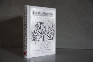 Black Snow Falling by L.J MacWhirter, hardcover novel with silver foil stamping on white cloth cover.